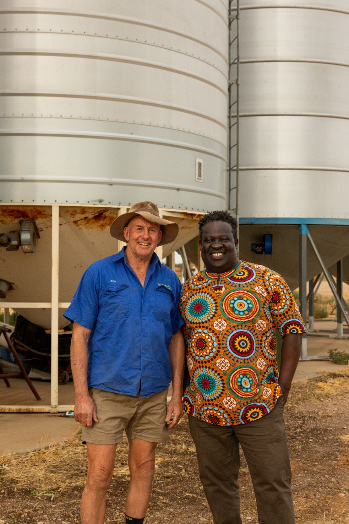 Rob and Ken standing together in front of grain silos on Rob's Riverina farm.